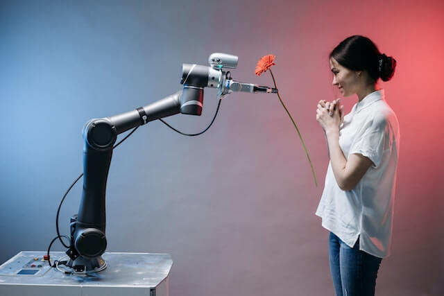 A robot arm giving a flower to a woman