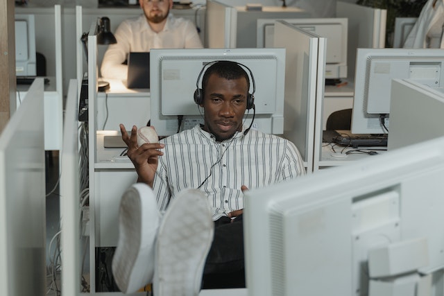 A man with a headset with his feet up on a desk