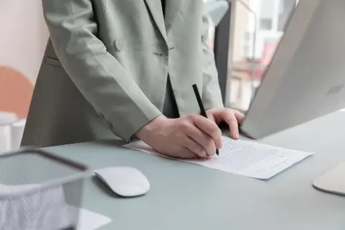 Woman Standing At Desk Writing
